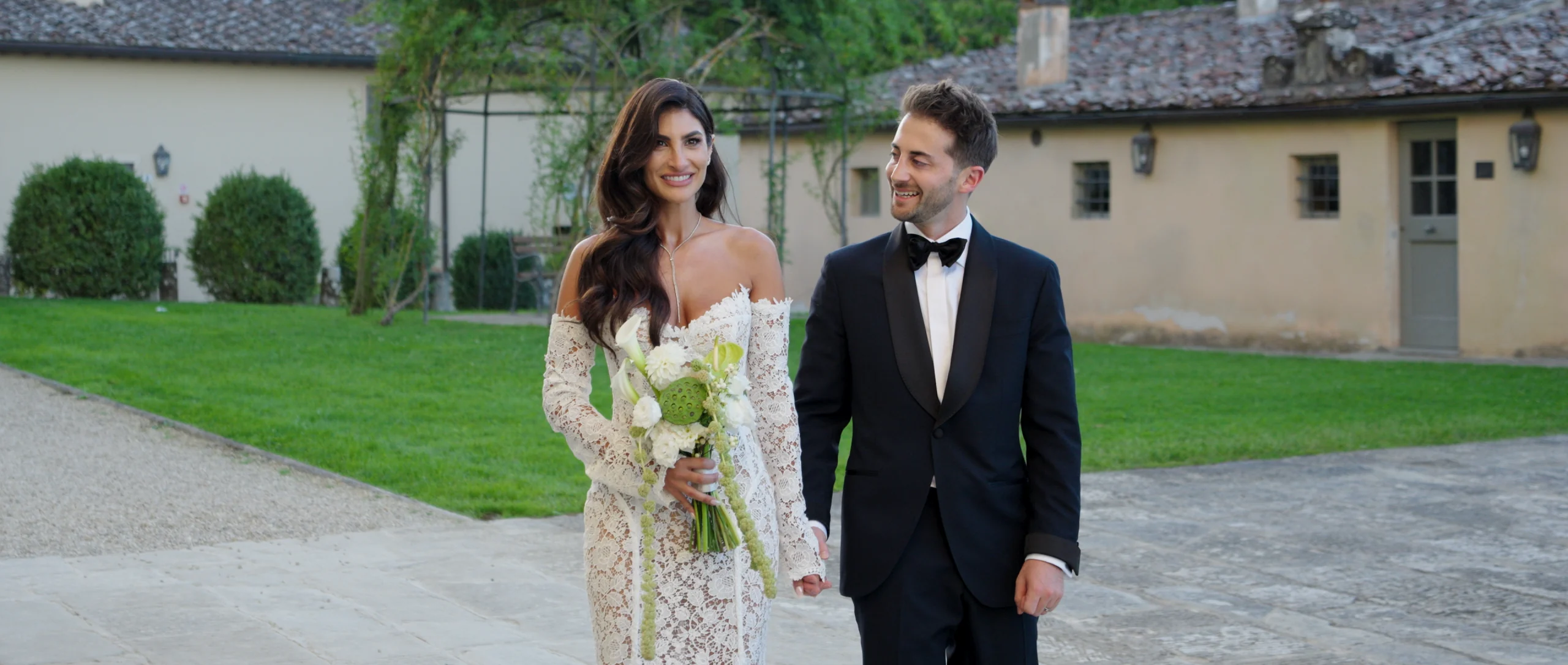 Danielle and Daniel walking together, with Danielle holding her bouquet